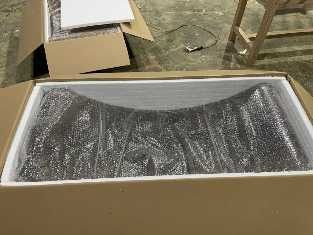 Gebogenes Holzbett, in Schaumstoff gebettet im Exportkarton.